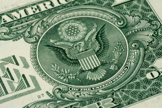 Macro close-up of a US dollar bill showing fine engraved details, eagle emblem, paper texture and printed currency patterns for finance, money and economic background concepts.