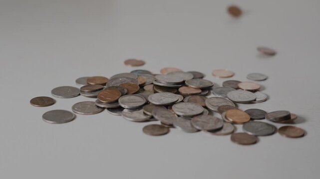 Loose american coins dropping and scattering on a white surface, creating a dynamic visual of financial accumulation and savings.