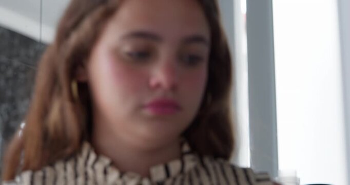 Young Girl's Contemplation: A young girl with long, flowing brown hair and subtle makeup looks down with a thoughtful and perhaps melancholic expression.
