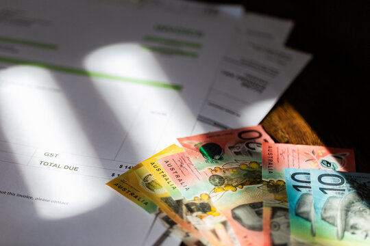 colourful Australian banknotes scattered on tax invoices small business accounting concept