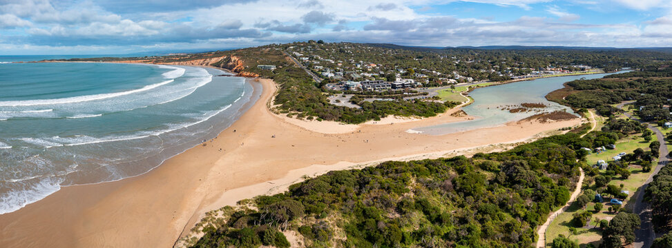 Aerial panorama view of a sand bar blocking a coastal river mouth alongside a seaside town