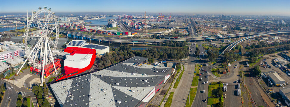 Aerial panorama view of freeways and shopping centres around a tourist ferris wheel near a city port
