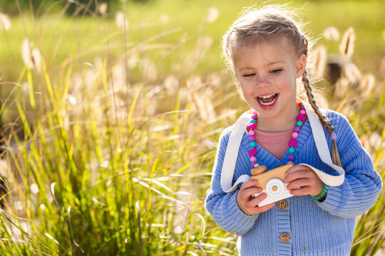 Child playing with toy wooden camera pretending to be a photographer