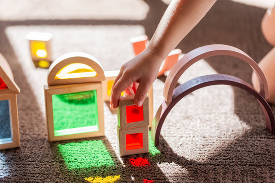 Light shining through colourful toy bocks set up by child on sunlit floor