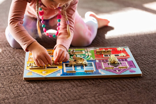 child working on colourful lock puzzle board on floor