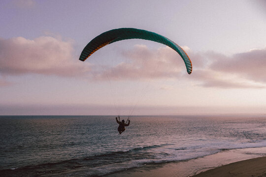 Paraglider soaring gracefully above the ocean at twilight
