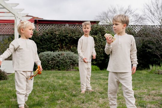 brothers standing in the backyard, one with a sandwich in hand