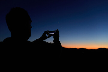 Amateur astronomer with smartphone photographing and observing stars, planets, Moon and other celestial objects. © astrosystem