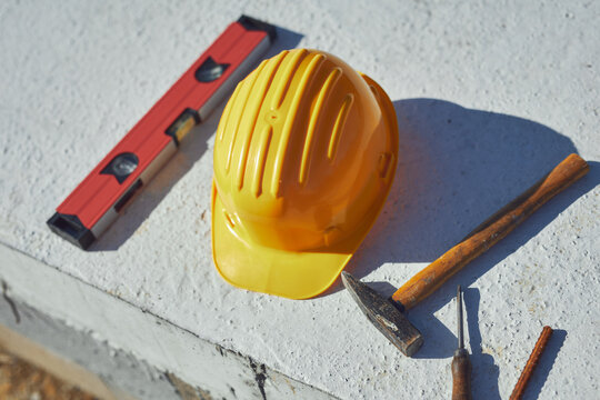 Construction tools and helmet on a cement foundation with iron rebar.