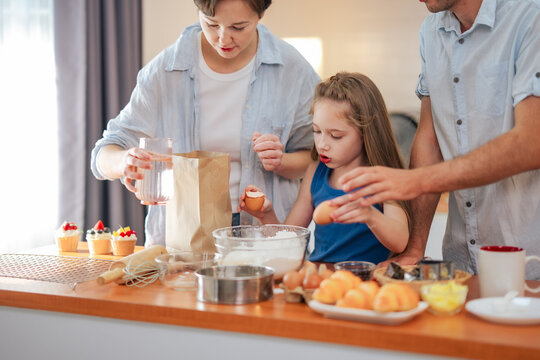 Family baking together at home while parents teaching daughter cooking. Homemade pastry, child learning, kitchen activity, family lifestyle, parenting, together.