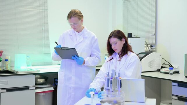 Team of scientists analyzing blue liquid samples in a modern lab, showcasing biotechnology, chemistry, and medical research innovation.