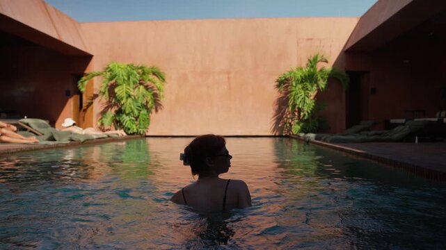 Silhouette of a woman relaxing in a luxury hotel pool