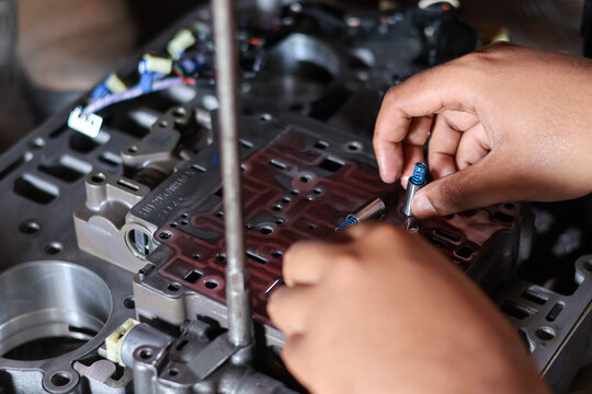 Mechanic installing check valves on transmission valve body.
