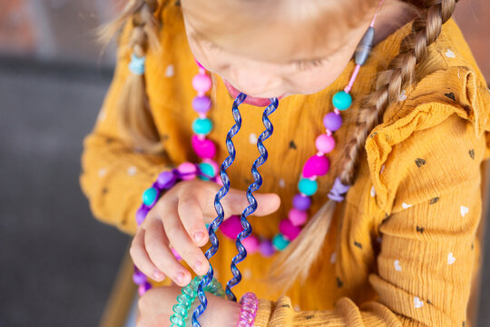 Little girl biting colourful chewelry bracelets for sensory stim