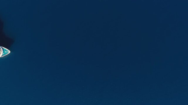Overhead aerial view of a luxury cruise ship entering the frame in open deep blue waters