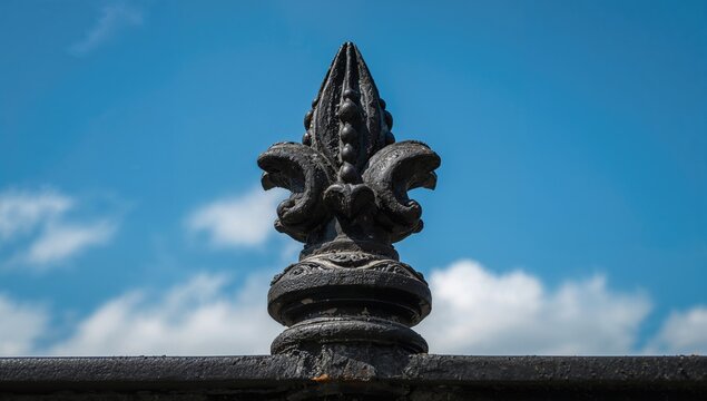 Decorative Black Iron Finial with Fleur-de-lis Design Against a Blue Sky