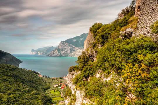 Landscape nature and rocky cliffs frame a scenic lake during an outdoor adventure travel experience in the destination of Arco, Trentino, Veneto, Italy.