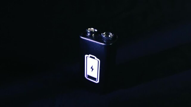 Luminous battery symbol with a lightning bolt glowing on a 9 volt battery against a dark background, illustrating concepts of power, charging, electricity, and energy storage technology