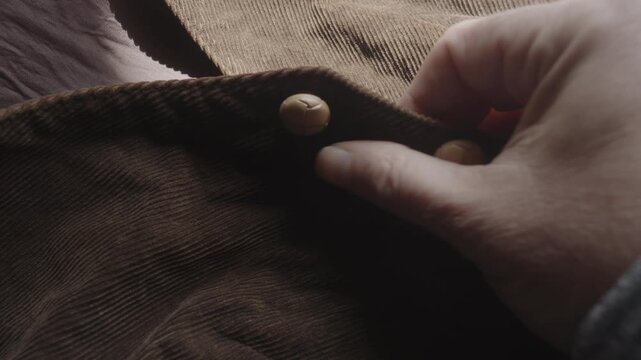 Close-up of fingers exploring the soft texture of a collarless corduroy jacket, highlighting tactile comfort, premium materials, and fashion craftsmanship.