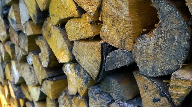 Close up view of a large pile of chopped firewood neatly stacked for winter, highlighting the natural wooden texture and pattern of the cut logs ready to be used as fuel