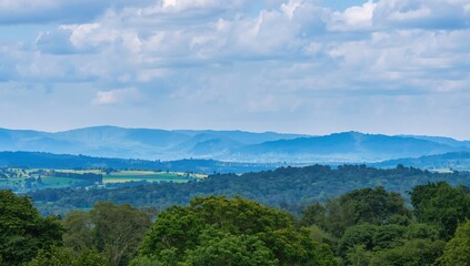 Obraz premium Mountainous Landscape Under Bright Blue Sky with Fluffy White Clouds