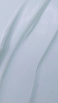 Stirring beauty cream slowly using a metal spoon. Vertical close up view for skincare theme. Smooth mixing texture for daily treatment concept.