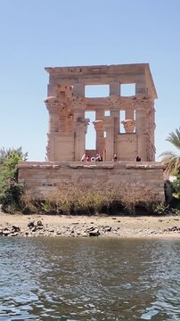 Historical kiosk of trajan, also known as pharaoh's bed, on the agilkia island in egypt, viewed from a boat navigating the nile river