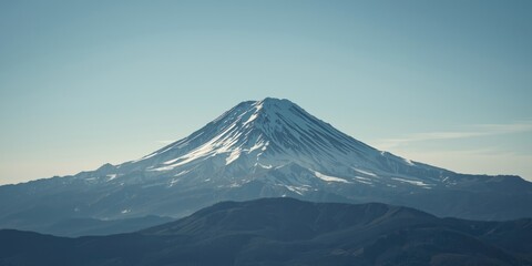 Fototapeta premium Snowcapped Mountain Peak Under Clear Blue Sky with Rolling Hills in Foreground
