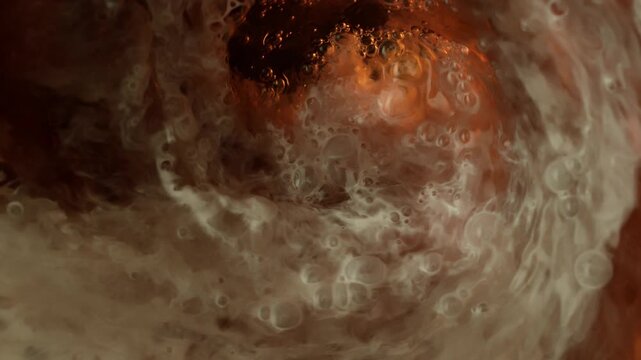 Super Slow Motion Shot of Swirling Cream Mixing in Coffee with Ice Cubes at 1000fps.