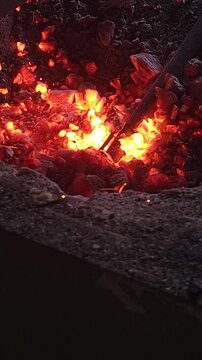 Close-up of a blacksmith forge with glowing burning hot coal and embers.