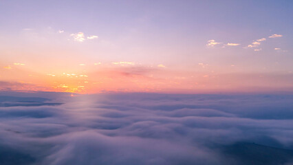 Fototapeta premium Turquoise and pink morning haze enveloping mountains and valleys below