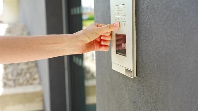 Person entering numbers on residential building intercom keypad. Secure access control enables visitor communication and controlled building entry