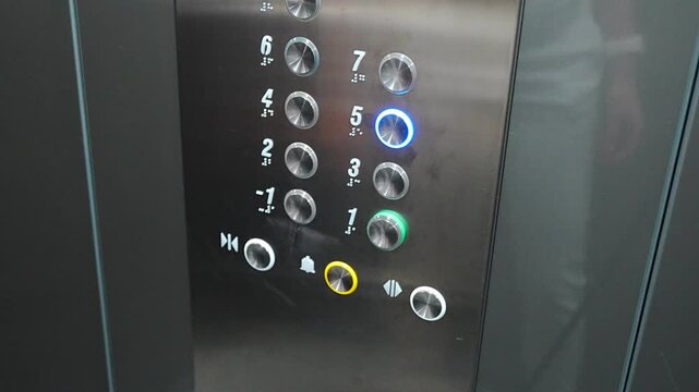 Person pressing the fifth floor button inside a modern elevator. Vertical transportation supports convenient access and efficient movement in residential buildings