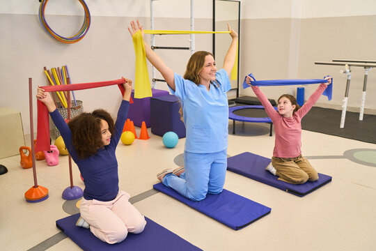 Pediatric Physical Therapy Session with Children and Therapist, Rehabilitation Exercises with Resistance Bands, Motor Skills Training in a Pediatric Rehab Center, Balance Training