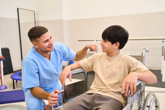 Pediatric rehabilitation with therapist and child in wheelchair, physical therapy session for disabled children, motor skills training and rehabilitation exercises in clinic, recovery support