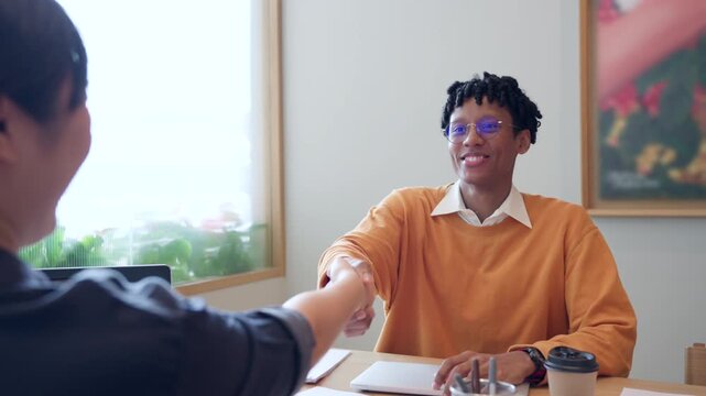 Cheerful African American businessman shaking hands with colleague after a successful meeting in modern office