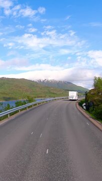 POV driving on a scenic mountain road in Norway with campers ahead.