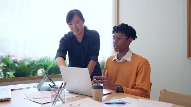 Diverse young colleagues working together on laptop computer in modern office, business collaboration concept