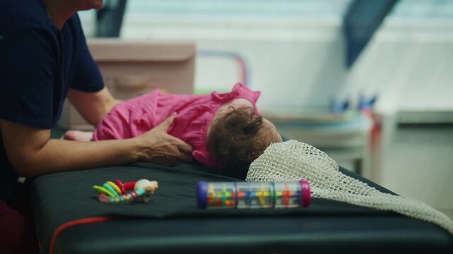 Baby lying on a changing surface while an adult gently offers a pacifier and toys, creating a calm everyday childcare scene