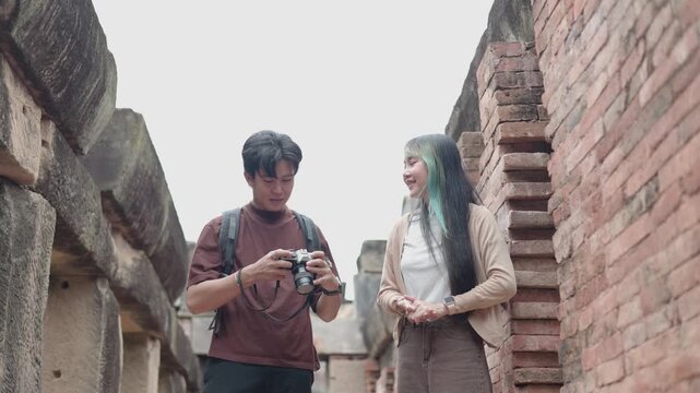 Young travelers exploring ancient stone ruins while reviewing photos on a digital camera. Travel photography, cultural heritage, historic architecture, adventure, tourism, backpacking,