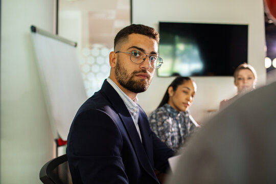 Focused young professional listening during office meeting