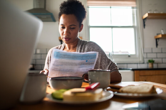 Woman reviewing household bills at kitchen table