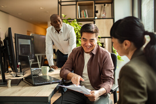 Three coworkers collaborating over documents in modern office
