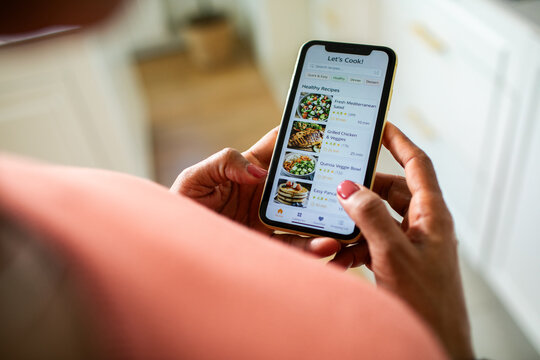Close-up of woman using recipe app on smartphone in home kitchen
