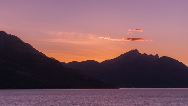 Mountain Silhouette Against a Purple Sunset over Calm Water