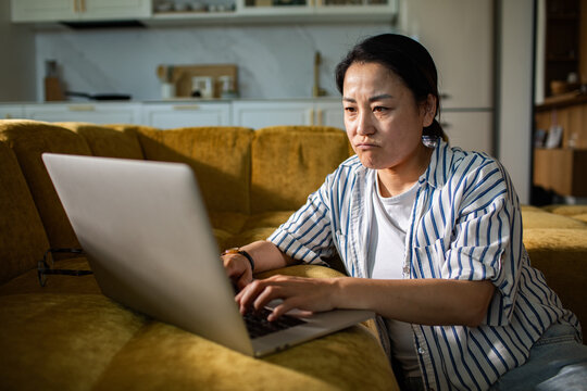 Frustrated woman using laptop on home sofa