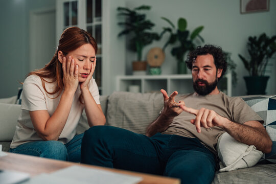 Couple having serious conversation at home, discussing relationship problems and conflict, feeling frustrated and stressed