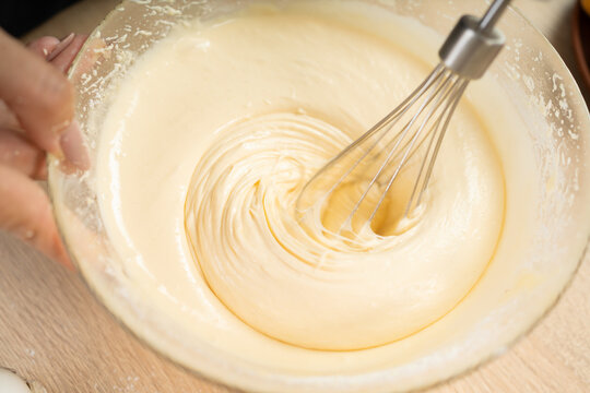 Close up of liquid batter whipped with electric mixer during sponge cake preparation for homemade baking.