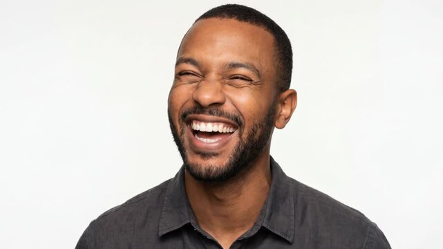 Close-up portrait of a Black man laughing out loud on white background. Cheerful African American male smiling and expressing joy. Happiness and positive emotion concept