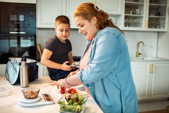 Parent and child preparing healthy lunch in home kitchen